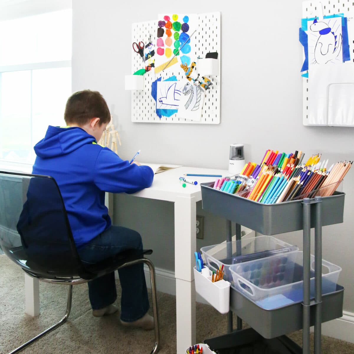 Boy working at a desk with an organized art cart for back to school