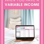 A laptop displaying a budgeting spreadsheet sits on a bed with white and pastel linens. Text above reads, "Budgeting tips for managing irregular income & why it’s so important!" with a web address at the bottom.